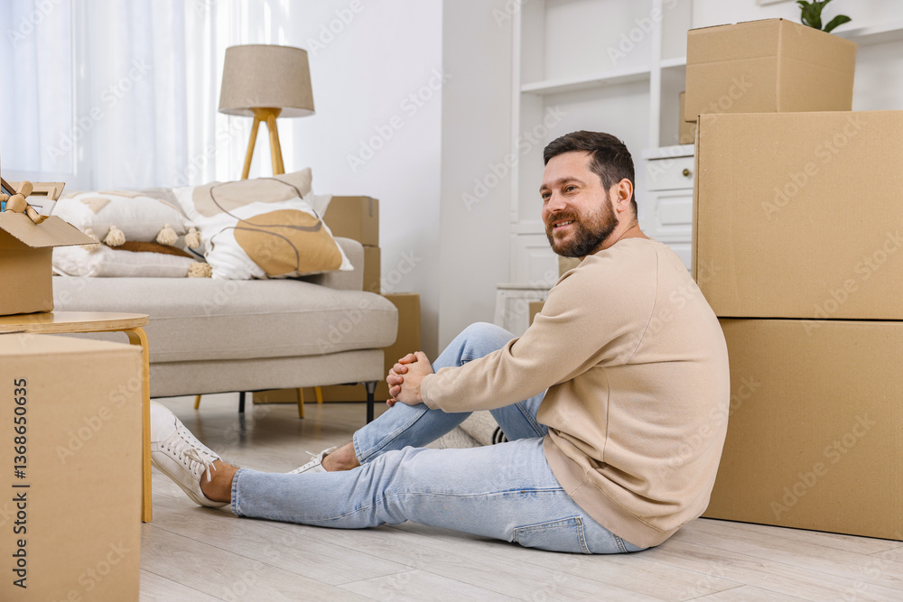 Moving day. Man resting on floor near cardboard boxes in his new home Moving day. Man resting on floor near cardboard boxes in his new home