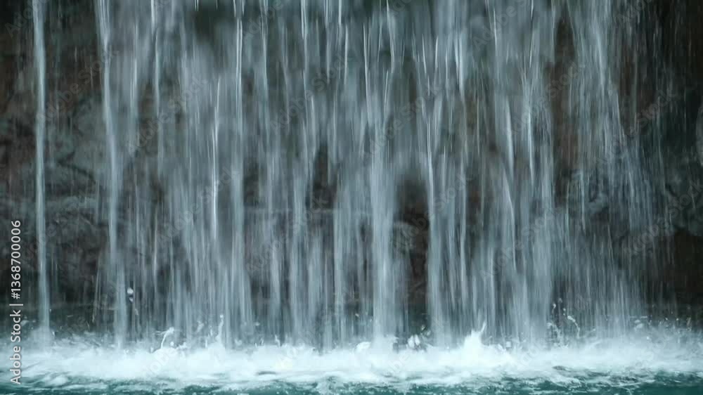 A waterfall flows fast into the pool