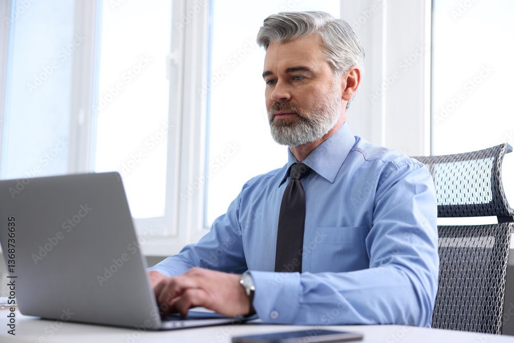 Banker working on laptop at desk in office