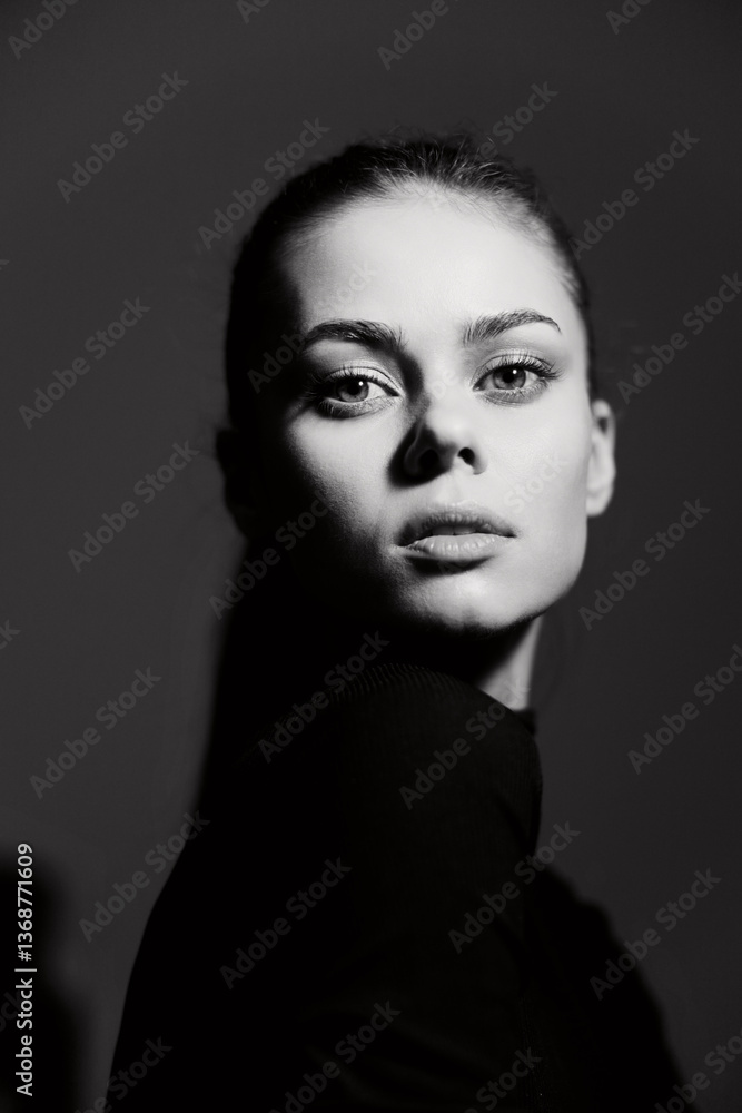 Serious young woman with striking features, posing in dramatic lighting, wearing a fitted black top. Artistic portrait showcasing elegance and confidence. Serious young woman with striking features, posing in dramatic lighting, wearing a fitted black top. Artistic portrait showcasing elegance and confidence.