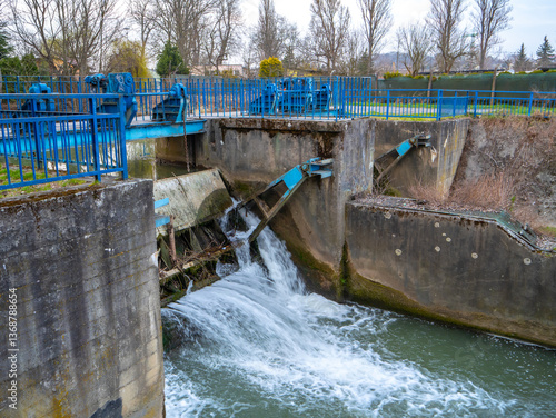 фотографія Small weir with flowing water and blue control mechanisms