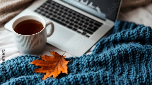 Cozy autumn workplace setup with laptop, hot beverage, and fall foliage