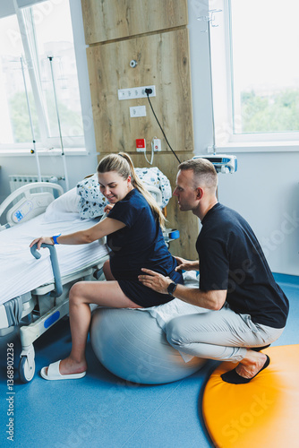 A man supports his wife during childbirth. A woman sits on a fitball during childbirth. A woman goes into labor in the delivery room.