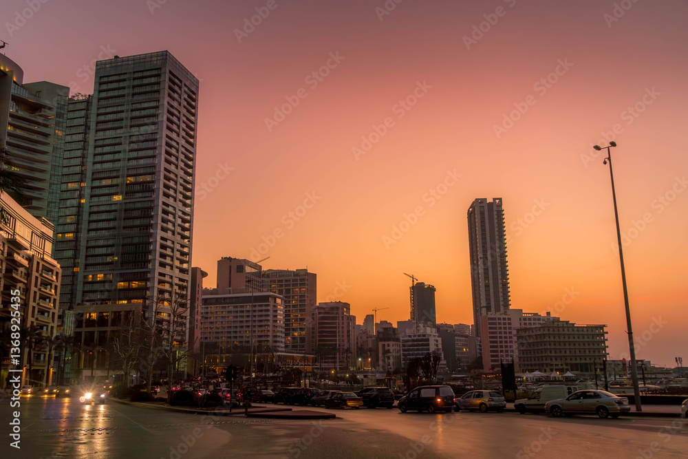 Obraz premium A captivating sunset view of Beirut Corniche, Lebanon, with lively locals on a vibrant promenade and iconic urban skyline. 