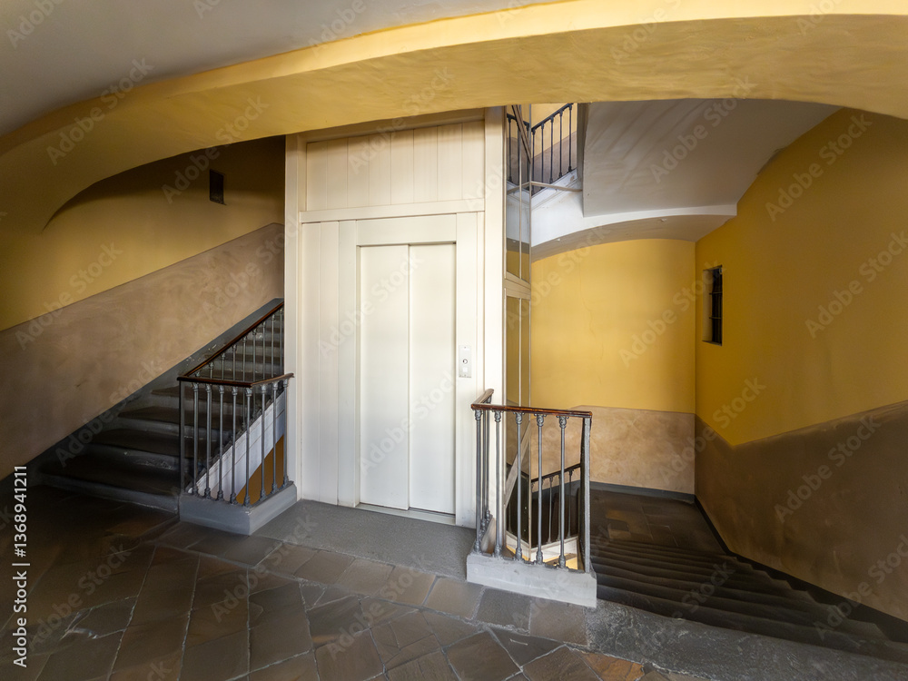 Obraz premium Landing with stone floor with elevator door built inside the stairwell of an old Italian 19th century building