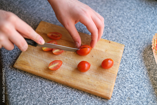 Child Cutting Cherry Tomatoes for Homemade Air Fryer Pizza
