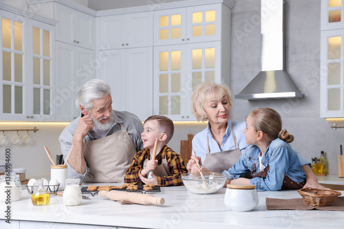 Grandparents and their grandkids cooking together at white marble table in kitchen photo