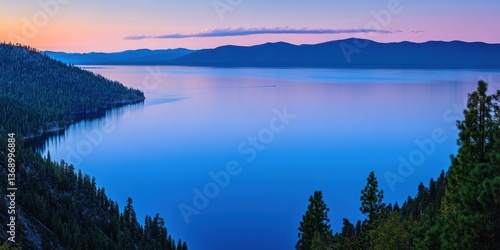 Serene lake view at dusk, showcasing calm waters and distant mountains under a twilight sky.