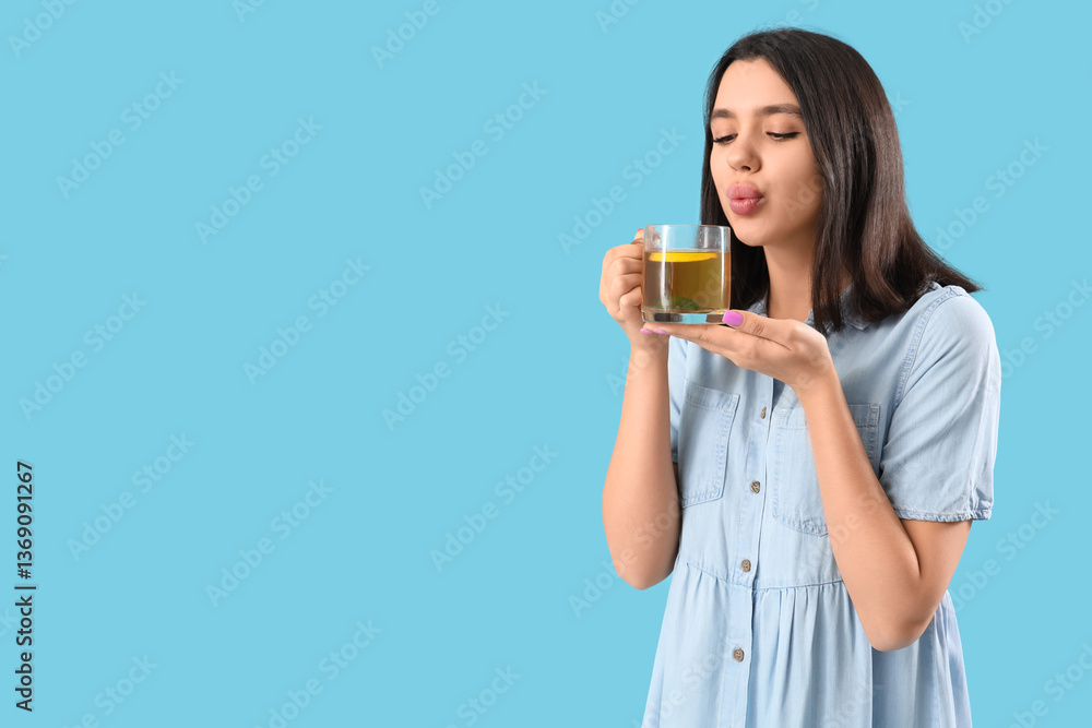 Young woman with glass cup of hot lemon tea on blue background Young woman with glass cup of hot lemon tea on blue background