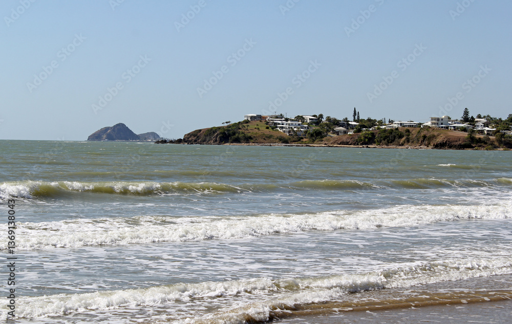 Φωτογραφία Waves of the ocean crashing on the sand of Yeppoon main beach with the town in t