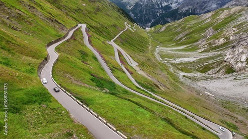 Drone shot of a sports car driving over the hairpin road of the Stelvio Pass, Italy