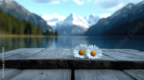 Serene lakefront scene with wildflowers. Two daisies rest on weathered wooden dock, overlooking a tranquil alpine lake reflecting snow-capped mountains and lush forest