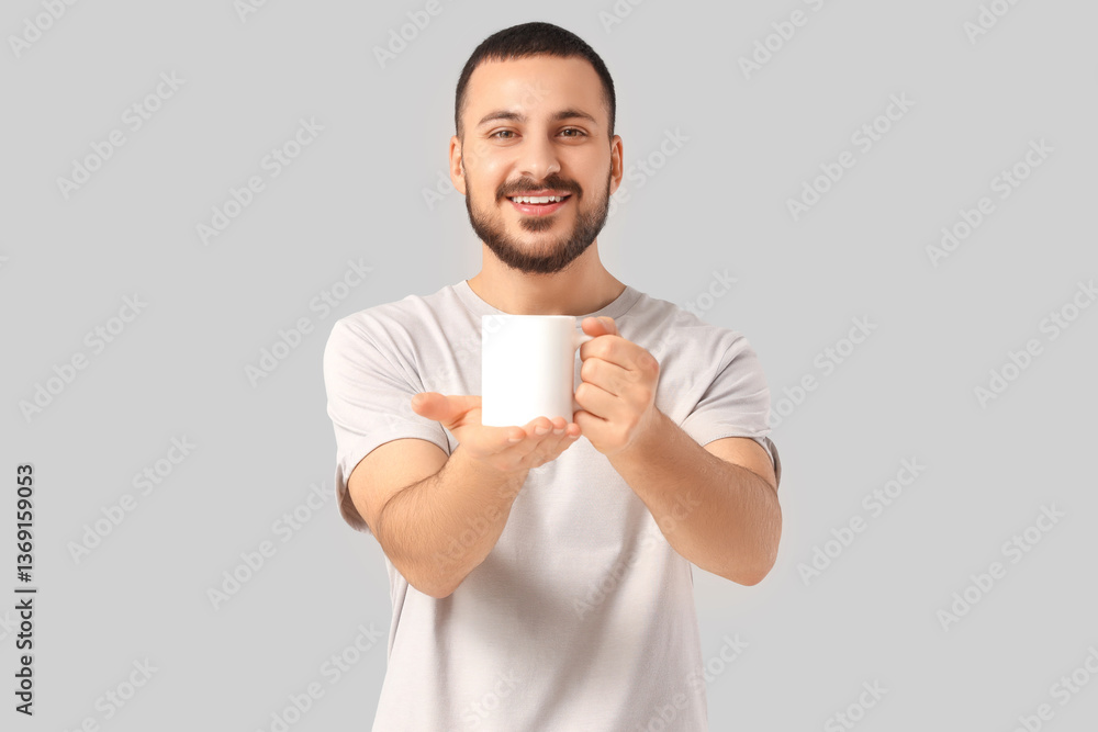 Handsome young man with cup of hot tea on grey background Handsome young man with cup of hot tea on grey background
