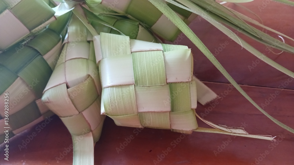 Close up view of Ketupat, an Indonesian traditional cuisine very popular during Hari Raya Idul Fitri served on a wooden table. This is made of the white rice, usually served with opor ayam on Ied day. Close up view of Ketupat, an Indonesian traditional cuisine very popular during Hari Raya Idul Fitri served on a wooden table. This is made of the white rice, usually served with opor ayam on Ied day.