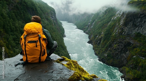 Hiker with Orange Backpack Overlooking a Misty River Valley