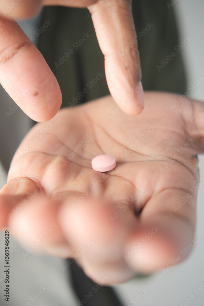 Hand holding a pink tablet in a thoughtful moment Hand holding a pink tablet in a thoughtful moment