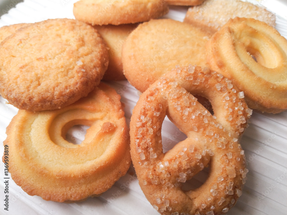 Close-up of assorted golden butter cookies with sugar sprinkles, arranged on a white surface. Close-up of assorted golden butter cookies with sugar sprinkles, arranged on a white surface.