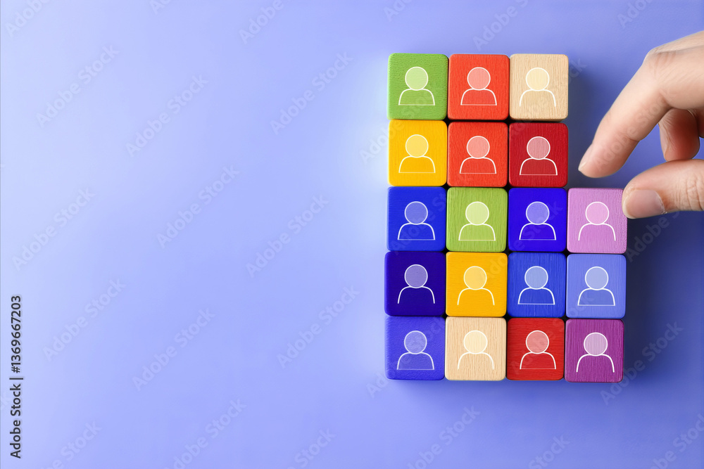 Business team and recruitment concept. A hand placing a wooden figure within a group Business team and recruitment concept. A hand placing a wooden figure within a group