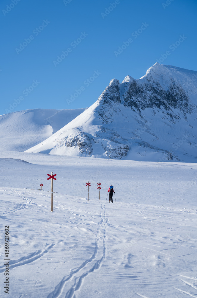 Woman cross-country skiing toward mountain Templet, in the Sylarna mountain range. Sweden.