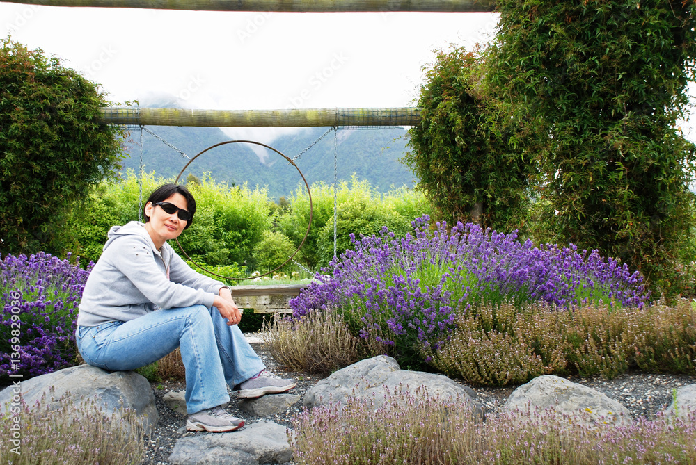 Woman sitting among lavender flowers. Otago. New Zealand.