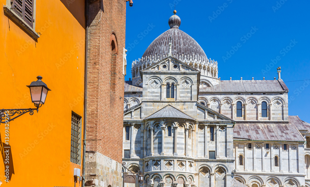 Historic Duomo cathedral in front of a colorful house in Pisa, Italy