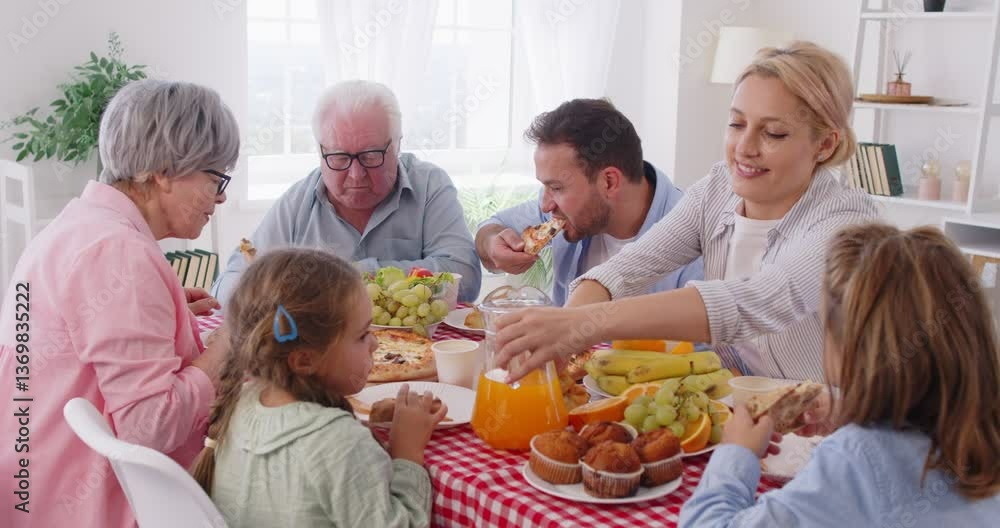 Happy big multi generation family sitting around table full of different food, eating pizza during dinner. Cheerful parents, grandparents and children enjoying meal together. Family bonds concept. Happy big multi generation family sitting around table full of different food, eating pizza during dinner. Cheerful parents, grandparents and children enjoying meal together. Family bonds concept.