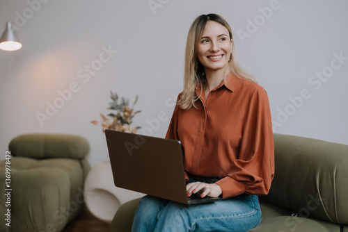 Young woman working on laptop in modern indoor space during daytime with a warm smile