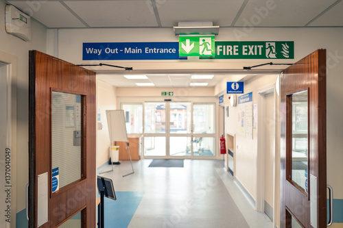 Shallow focus of a typical illuminated Fire Exit sign seen within an NHS hospital outpatients department. The fire exit leads to the car park and the AE department.