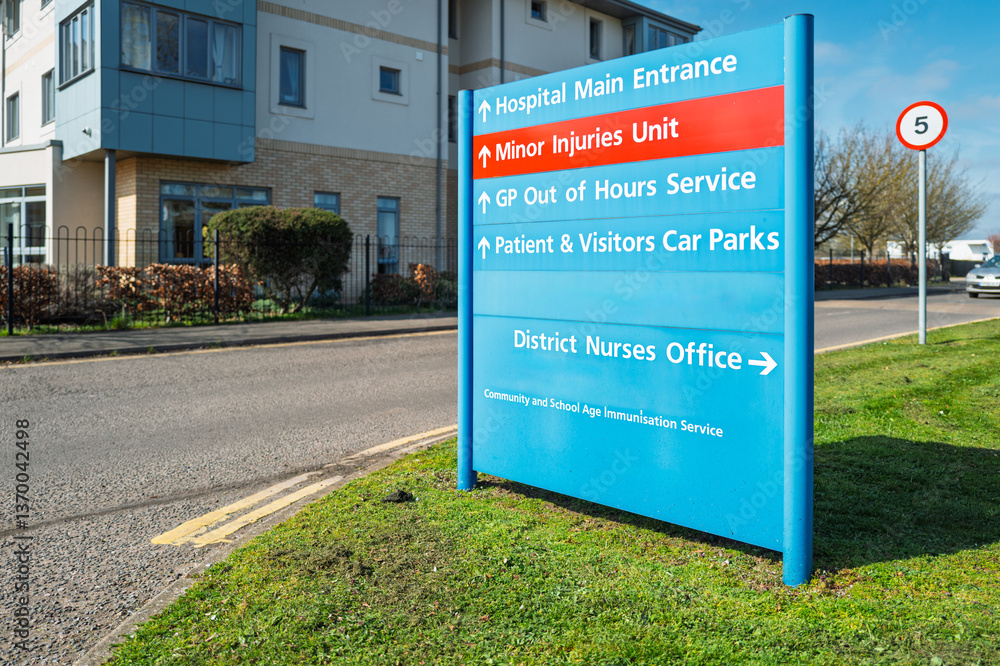 Large, NHS type information sign showing outpatients department, out of hours doctors and a minor injury unit. Located at the entrance to the large hospital campus.