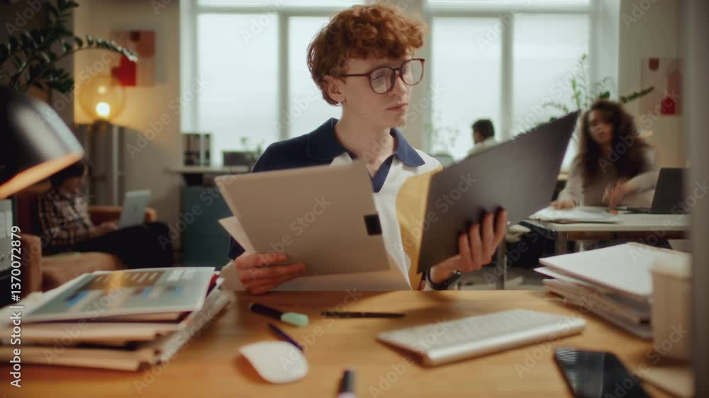 Young man handling paperwork, taking notes, typing on computer and answering phone calls during busy workday in modern office. Time lapse video Young man handling paperwork, taking notes, typing on computer and answering phone calls during busy workday in modern office. Time lapse video