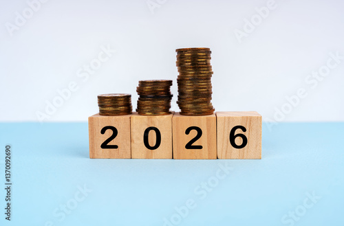 2026 written on wood blocks with coins stacked on them. New Year plan concept