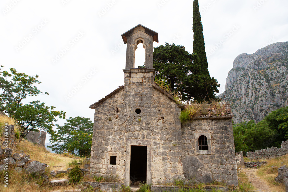 Ruined stone church stands overlooking a mountainous landscape in Montenegro, showcasing its weathered beauty and historical significance Ruined stone church stands overlooking a mountainous landscape in Montenegro, showcasing its weathered beauty and historical significance