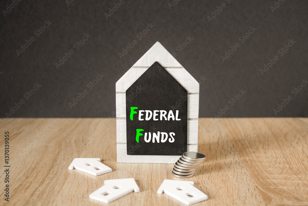 Concept words FEDERAL FUNDS on black blackboard. Beautiful wooden table, black background. A stack of coins. Business concept.