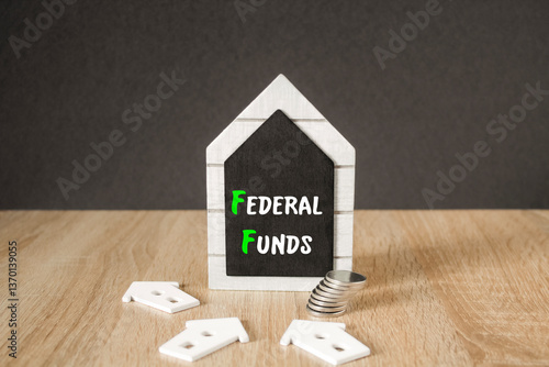 Concept words FEDERAL FUNDS on black blackboard. Beautiful wooden table, black background. A stack of coins. Business concept.