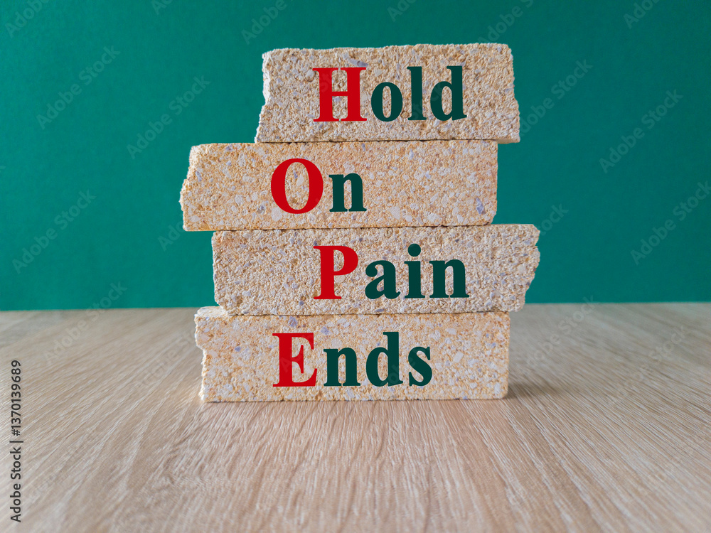 HOPE, hold on, pain ends symbol. Concept words 'HOPE, hold on, pain ends. on brick blocks. Beautiful green background, wooden table. Business and motivational concept.