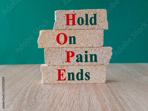 Obraz na płótnie HOPE, hold on, pain ends symbol. Concept words 'HOPE, hold on, pain ends. on brick blocks. Beautiful green background, wooden table. Business and motivational concept. w salonie