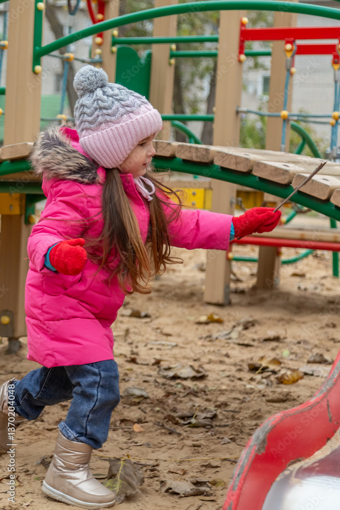 Obraz premium Little girl having fun on playground. Happy healthy little child climbing, swinging and sliding on different equipment. Child on cold day in colorful clothes outdoors