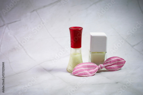 Two colorful nail polish bottles and a pink bow on a table