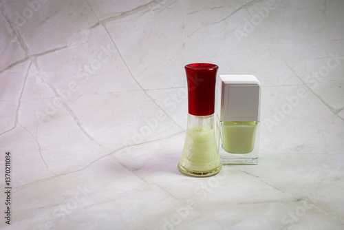A bottle of nail polish is next to another nail polish bottle