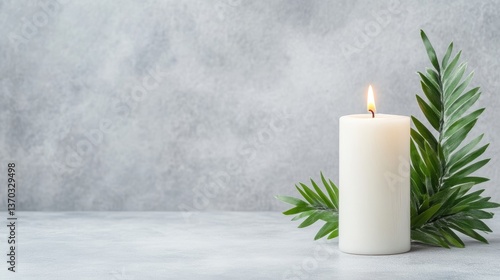 Simple candle and palm leaves on a gray surface