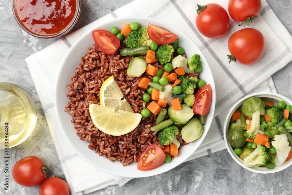 Delicious brown rice with vegetables and lemon slices served on grey textured table, flat lay Delicious brown rice with vegetables and lemon slices served on grey textured table, flat lay
