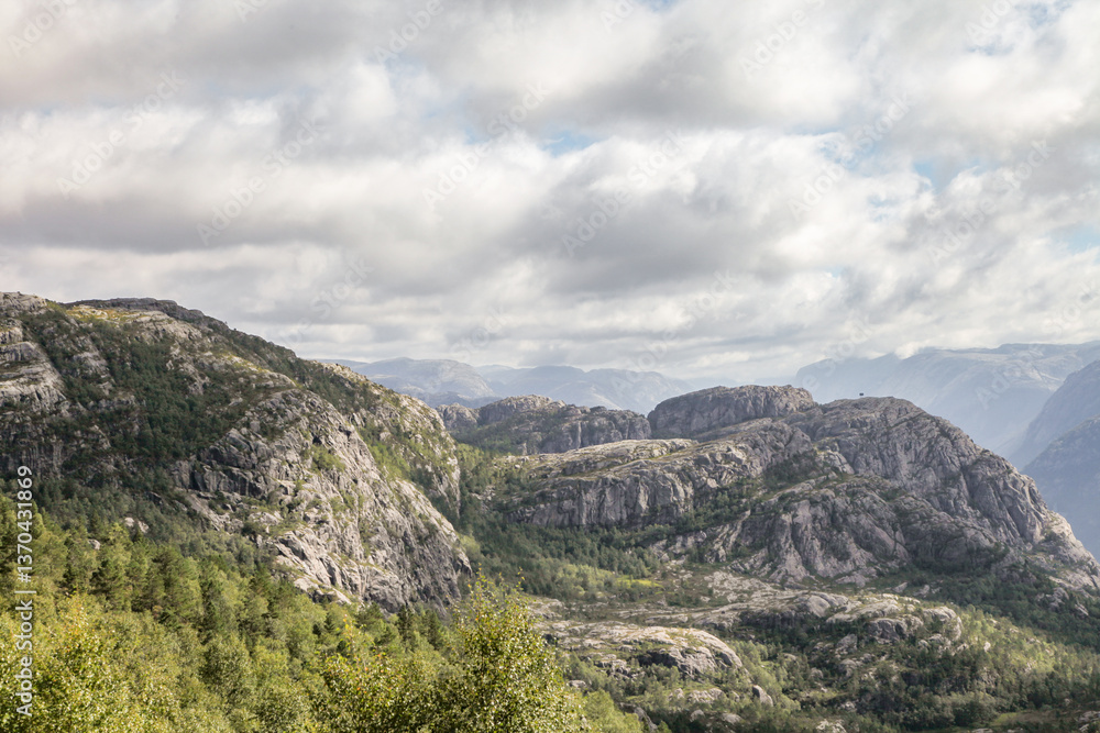 Fototapeta premium The mountains are covered in trees and rocks in Norway, and the sky is cloudy
