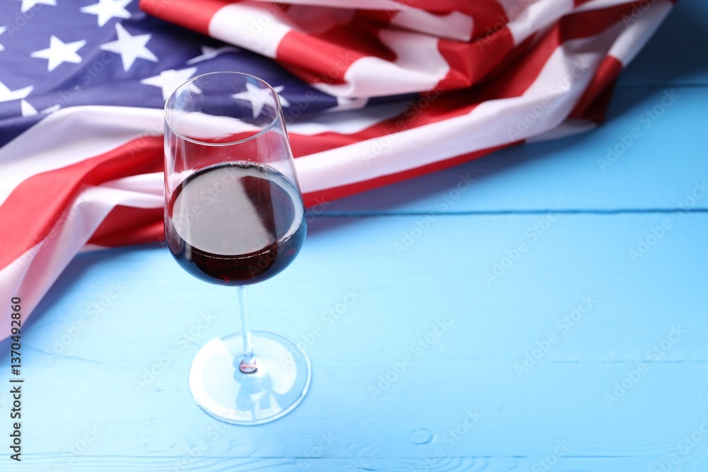 Glass of wine and American flag on blue wooden table. Space for text