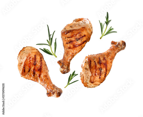 Fotografie Grilled chicken legs or drumsticks falling down with herbs and colourful peppers isolated on white background