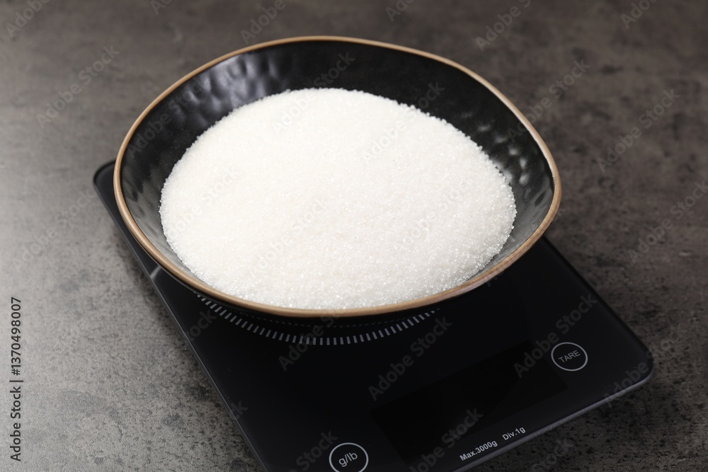 Digital kitchen scale with bowl of sugar on grey table, closeup Digital kitchen scale with bowl of sugar on grey table, closeup