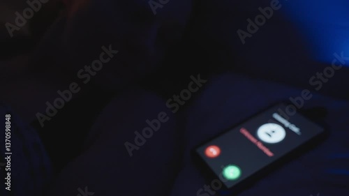 Incoming Call from Unknown Number Appears on Smartphone Screen Resting on Bed in Dark Room with Blue Light, Close-Up Angle, Late Night Disturbance Concept