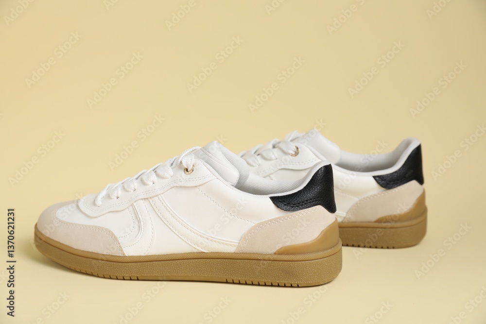 Pair of stylish sneakers on beige background. Casual shoes