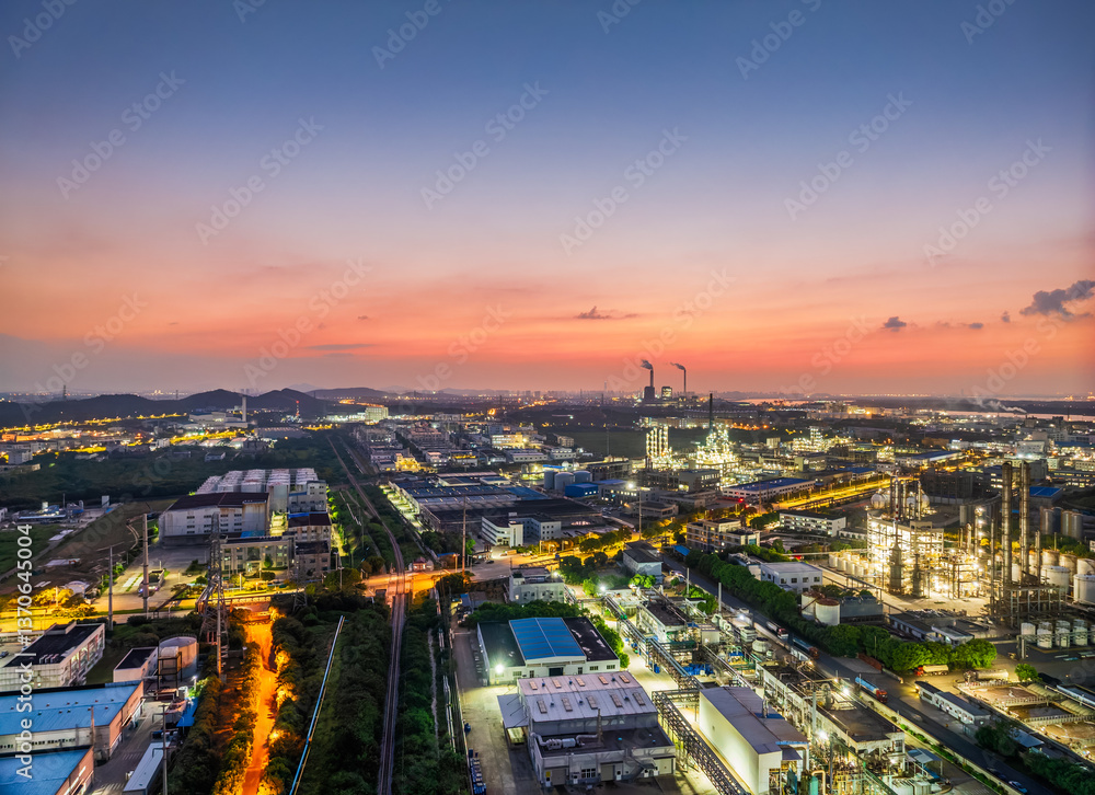 Fototapeta premium Aerial view of sprawling industrial complex with colorful sky at dusk
