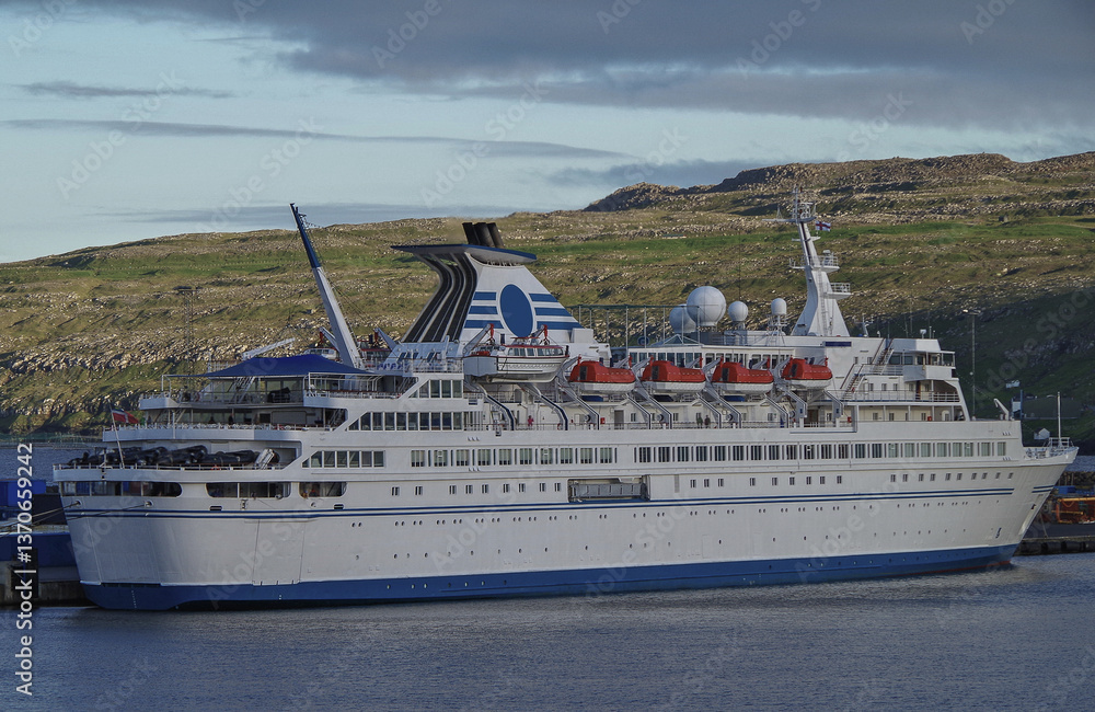 Classic expedition cruiseship cruise ship liner Delphin docked at terminal in Thorshavn Thorshaven, Faroe Islands with city skyline fjord landscape in background during Arctic Circle summer cruising