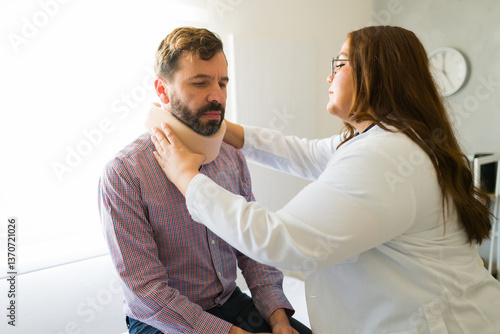 Obraz na plátně Doctor carefully adjusting cervical collar on male patient suffering from neck p